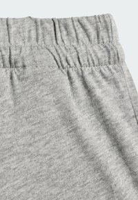 Tela de sudadera gris con una cinturilla elástica, con una textura suave y un ligero estiramiento, que muestra sutiles variaciones en la fibra.