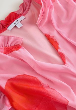 Blusa trasparente rosa con maniche a ruffo, scollatura a V profonda e motivi ad acquerello rossi. Etichetta con scritto "NEXT". Tessuto morbido e leggero.