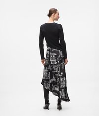 Top negru cu maneci lungi, combinat cu o fustă asimetrică ce prezintă schițe arhitecturale albe pe un fundal negru. Pantofii cu toc înalt completează look-ul.