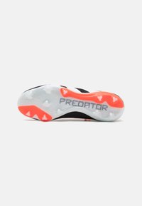 Suola di scarpa da calcio in bianco e nero con un design traslucido, caratterizzata da dettagli accentuati in rosso e la parola "PREDATOR" in argento.