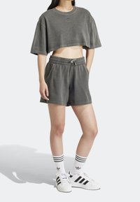 Gray cropped sweatshirt with dropped shoulders, matching gray shorts, and white shoes with black stripes, paired with striped white socks.