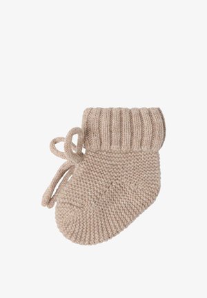 Beige strikket babyvante med ribbet manchet og snørelukning, isoleret på hvid baggrund.