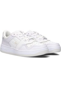 Baskets blanches en cuir synthétique, avec un design à tige basse, des accents perforés et une semelle en caoutchouc texturée. Détail du logo présent.