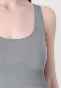Gray tank top with a smooth, stretchy fabric and a scoop neckline; features ribbed detailing along the bottom hem and shoulder straps.