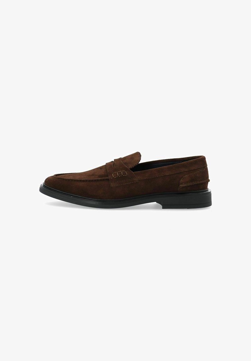 Mocassins en suède marron avec un bout arrondi, présentant une bande décorative cousue à l'avant et une semelle en caoutchouc noire.