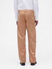 Μπεζ παντελόνι με φαρδιά μπατζάκια από λείο ύφασμα, με δύο πίσω τσέπες και εφαρμοστή μέση. Συνδυάζεται με λευκό πουκάμισο.