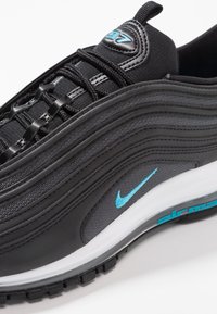 Schwarzer Sneaker mit geschwungenen Linien, aus Mesh- und Leder-Materialien. Verfügt über ein blaues Nike-Logo, Schnürsenkel und eine Sohle aus weißem und dunklem Gummi.