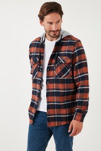Flannel skjorte i orange, marineblå og hvid plaid mønster. Har en grå hætte, to forhånds lommer og knaplukning. Blød tekstur.