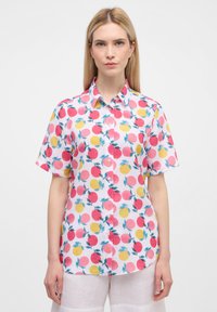 Camicia a maniche corte con bottoni in un tessuto rosa che presenta un motivo di cerchi rossi e gialli con foglie verdi. Orlo arrotondato e vestibilità rilassata.