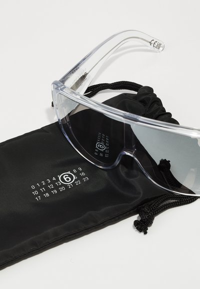 Klart skyddsglasögon med tonade linser, med transparenta bågar och en svart dragsko-påse tryckt med en numerisk skala.