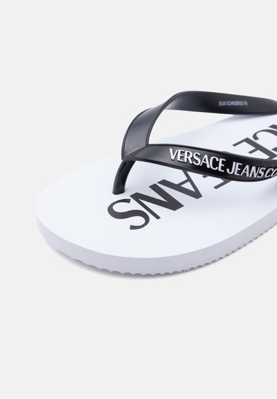 Бял джапанки с черни презрамки, с надпис "VERSACE JEANS" на презрамките и подметката.