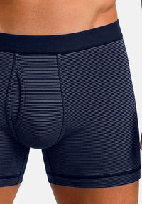 Laivastonsiniset raidalliset bokserit, joissa on pehmeä joustava vyötärönauha, muotoiltu pussi ja ommellut reunat kestävyyden lisäämiseksi.