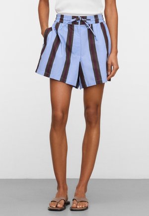 Persoon draagt losse shorts met verticale blauwe en zwarte strepen, elastische tailleband met koordje, gecombineerd met teenslippers.