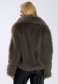 Teksturowana kurtka z sztucznego futra w stonowanym szaro-brązowym kolorze, z szerokim kołnierzem i długimi rękawami, charakteryzująca się luźnym, swobodnym krojem oraz prążkowanymi detalami.