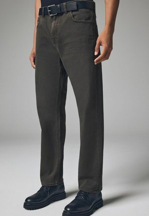 Mörkgröna denimjeans med rak benklippning, detaljerad sömnad och ett svart bälte. Matchas med svarta läderskor.