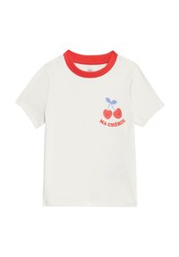 T-shirt bianco a coste con colletto a girocollo rosso. La parte anteriore presenta una grafica di due ciliegie rosse sorridenti e il testo "MA CHÉRIE" in rosso.