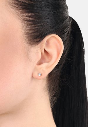 Silver stud earring featuring a geometric design with a central clear gemstone and surrounding accents, displayed against a neutral background.