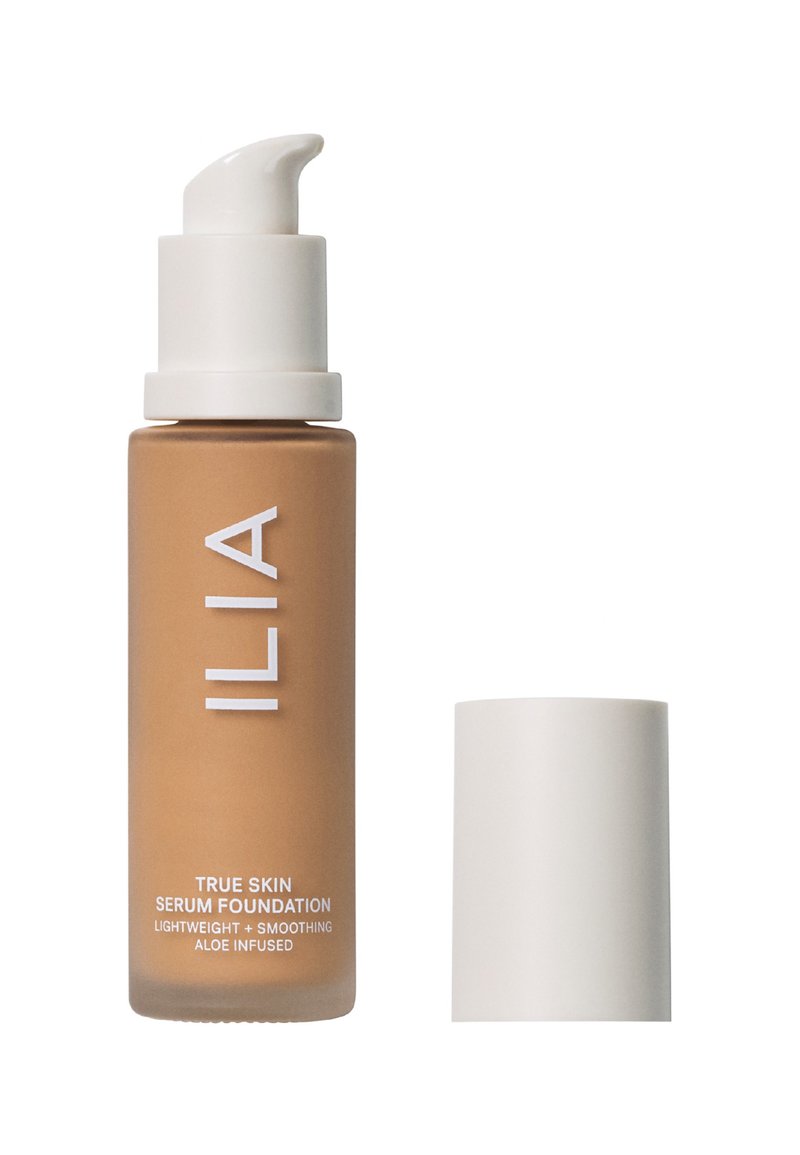 Flaske med ILIA True Skin Serum Foundation i en myk brun nyanse, med en hvit pumpe og hette. Designet er strømlinjeformet med minimalt med tekst.