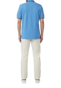 Lichtblauw polo-shirt met korte mouwen, voorzien van een klassieke kraag en marineblauwe accenten, gecombineerd met off-white broek en witte sneakers.