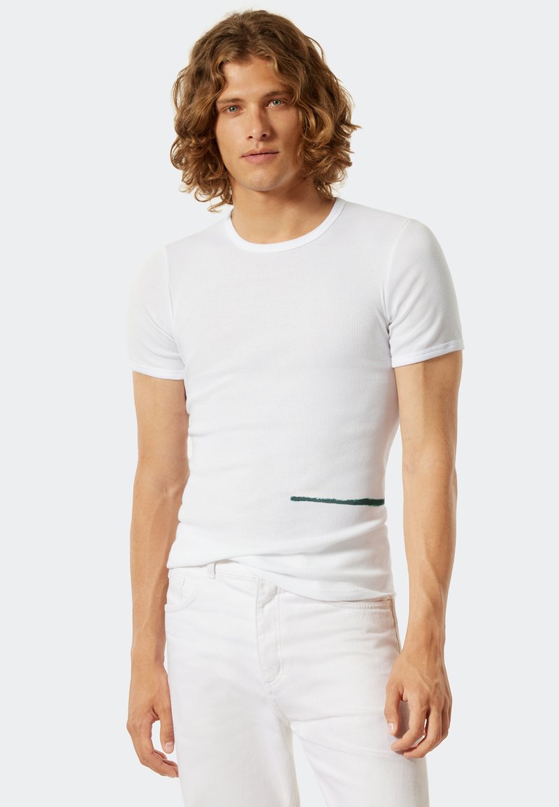 Weißes, geripptes T-Shirt mit kurzen Ärmeln und einem grünen horizontalen Akzent auf der linken Seite. Designed für einen figurbetonten Look. Hergestellt aus weichem Baumwollmaterial.