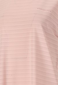 Vaaleanpunainen urheilupaita, jossa on teksturoitu, raidallinen kuvio. Paidassa on sana "ENDURANCE" kirjoitettuna hienovaraisesti tummemmalla sävyllä.