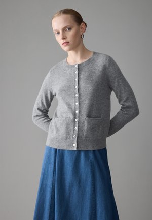 Grå ull cardigan med knappelukking, rund hals, to lommer og lange ermer. Kombinert med et blårutete denimskjørt.