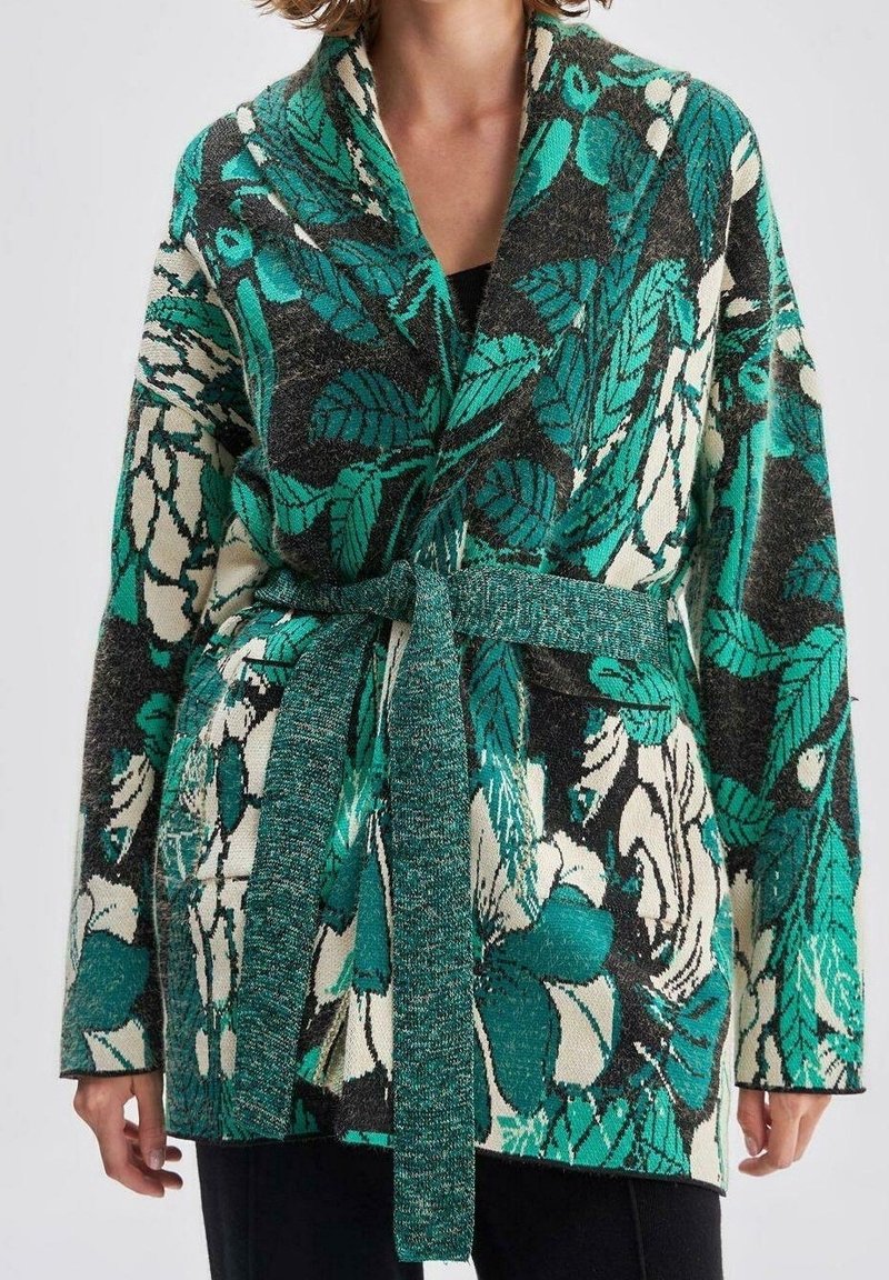 Grøn og sort blomsterprintet cardigan lavet af struktureret stof, med sjalkrave, åben front og et matchende bælte bundet i taljen.