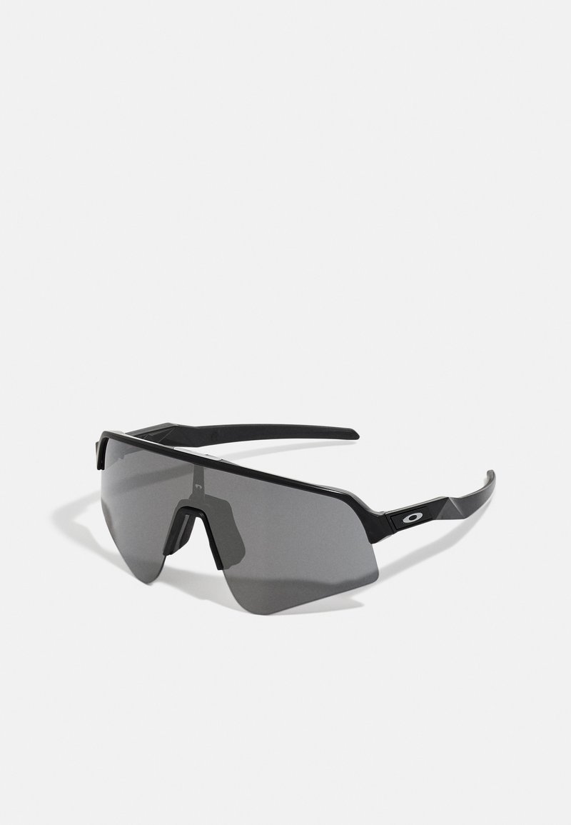 Ochelari de soare negri cu un design plat și unghiular. Lentile mari și întunecate, ramă robustă și un pod nazal distinctiv. Branding minimalist pe lateral.