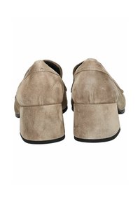 Zapatos de ante beige con un tacón bajo y cuadrado, con un diseño simple y bordes redondeados, vistos desde la parte posterior. Sin hardware ni acentos visibles.