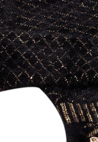 Svart, fluffig textil med ett diamantmönster och metalliska guldtrådsdetaljer. Texturen är mjuk med varierande glans från paljetter.