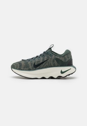 Ciemnozielony i szary wzorzysty but do biegania Nike z czarnymi logo swoosh i grubą białą podeszwą środkową z zielonym detalem swoosh.