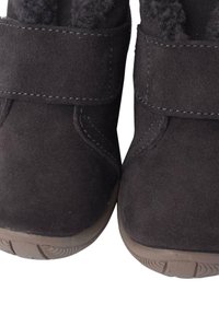 Las botas de tobillo de ante negro cuentan con una suela de goma plana, cierres de correa de Velcro y un forro texturizado para mayor calidez.