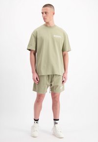 Olijfgroene katoenen T-shirt met een ruime pasvorm en korte mouwen, gecombineerd met bijpassende shorts met een trekkoord en logodetail.