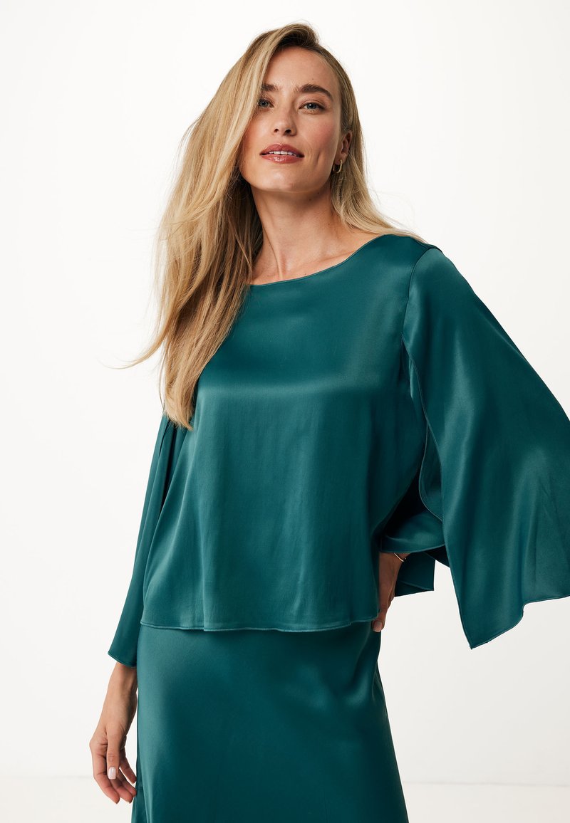 Top in satin color teal con vestibilità ampia, scollo a barca e maniche larghe. Texture morbida e caduta fluida. Design minimalista, senza motivi o accessori visibili.