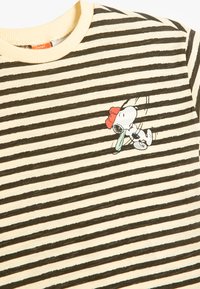 Camiseta a rayas con franjas alternas en negro y crema, con un cuello de canalé y un gráfico bordado de Snoopy con un sombrero rojo.