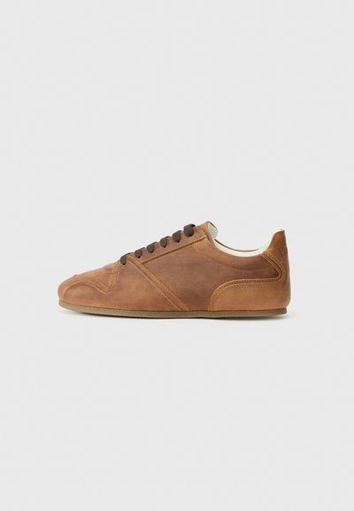 Sneaker en cuir brun avec un bout arrondi, surface texturée, accents superposés et lacets bruns. Il dispose d'une semelle en caoutchouc et d'un design minimaliste.