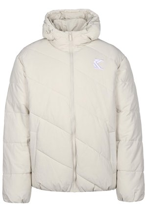Chaqueta de plumas beige claro con un alto cuello, patrón acolchado diagonal, cierre de cremallera y un pequeño logo blanco en el lado izquierdo del pecho.