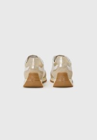 Baskets pour hommes avec un dessus combinant du daim beige clair et du mesh argenté, munies d'une semelle en caoutchouc beige et d'un détail logo au niveau du talon.