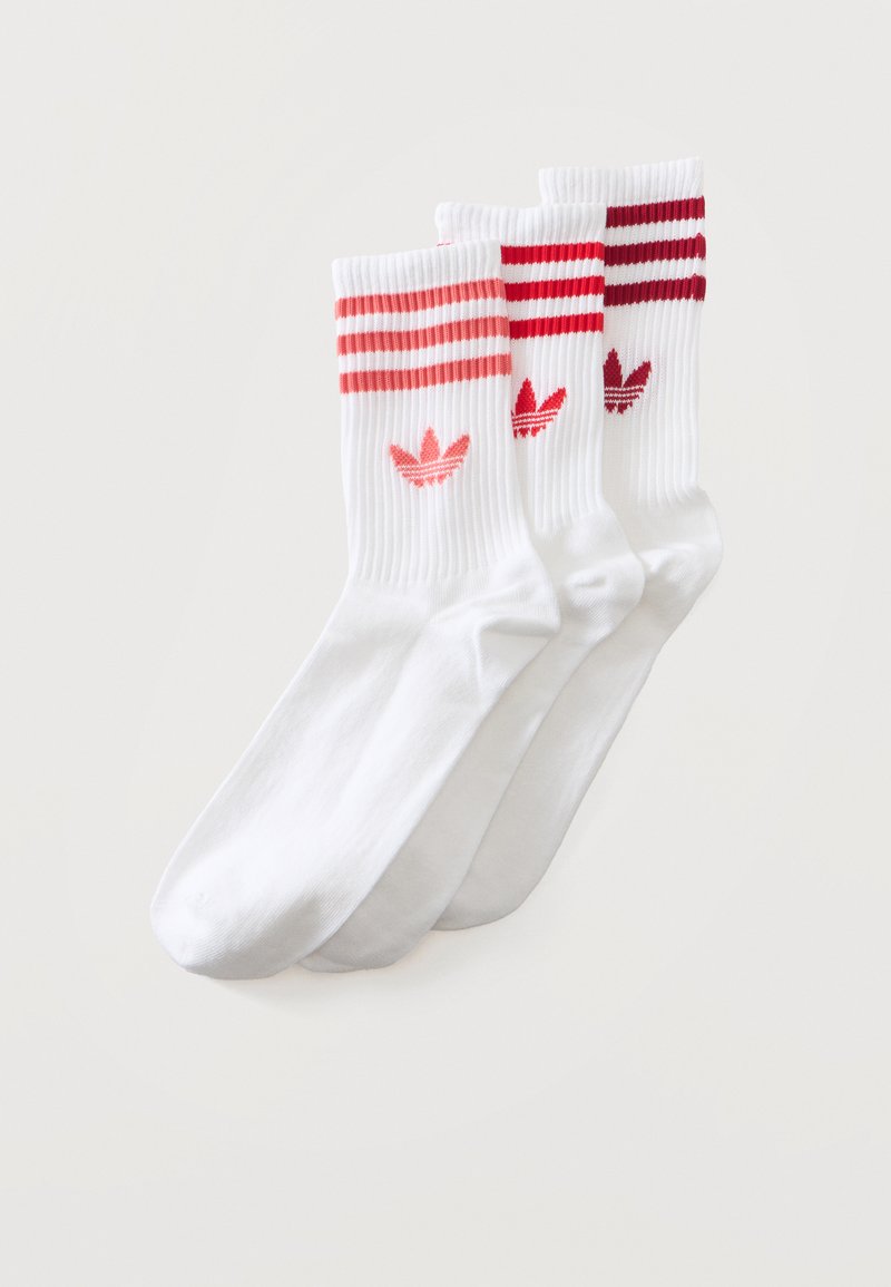Trois paires de chaussettes montantes Adidas blanches avec des bandes rouges, roses et bordeaux et des logos Adidas Trefoil assortis près du haut.