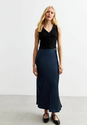 Black ribbed button-up crop top and a navy satin maxi skirt. The skirt has a smooth sheen and a flared hem, paired with black flat shoes.