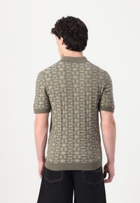 Pleteni polo majica u maslinasto zelenoj boji s geometrijskim jacquard uzorkom, kratkim rukavima te detaljima od rebraste tkanine na ovratniku i rubovima.