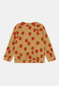 Blusa de manga larga en una tela marrón claro, con un patrón repetido de fresas rojas. El dobladillo está recogido, realzando el diseño informal.
