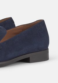 Tumedate nahkkingast loafers madala plokknäoga ja pehme välispindaga. Omab sujuvat disaini ja minimaalset õmbluste detaili.