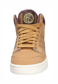 Wysokie trampki do koszykówki z brązowej skóry o teksturowanej powierzchni, z złotymi akcentami, perforowanym noskiem oraz brązowym futerkiem wokół kołnierza.