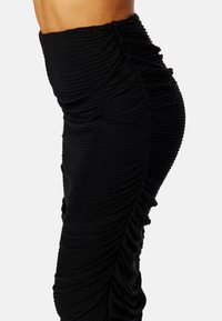 Czarna spódnica marszczona z teksturowanej tkaniny. Posiada wysoki stan oraz widoczne detale szwów, podkreślające dopasowany krój.