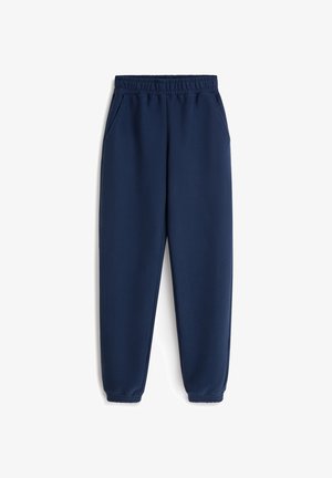 Granatowe spodnie dresowe wykonane z miękkiego materiału, z elastycznym pasem, bocznymi kieszeniami oraz elastycznymi mankietami przy kostkach.