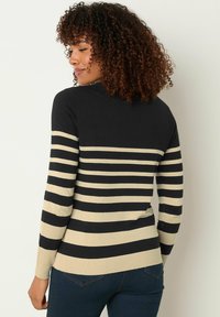 Gestreifter Pullover in Schwarz und Beige, aus Strickmaterial, mit langen Ärmeln und taillierter Passform. Mit geripptem Saum und Bündchen.