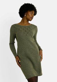 Vestido de punto en verde oliva con mangas largas, escote en forma de barco y detalles de encaje en el pecho. Textura suave, estilo ajustado, hasta la rodilla.