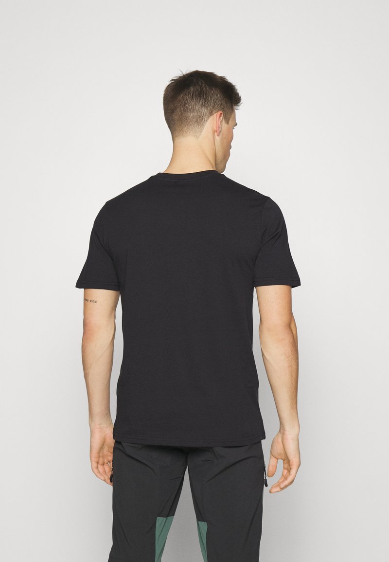 Vista posterior de una camiseta de algodón negra con cuello redondo y mangas cortas, que presenta una textura suave y costuras mínimas.