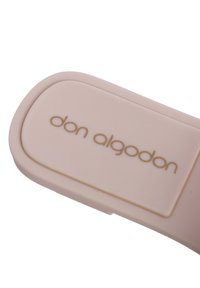 Objeto de silicona de color rosa pálido con bordes redondeados, que presenta una superficie texturizada y un logo en relieve dorado que dice "don algodon".